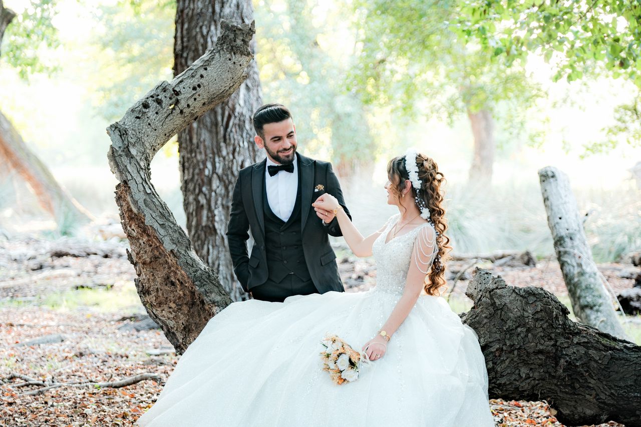 A bride and groom pose in a picturesque forest setting during their wedding photoshoot.