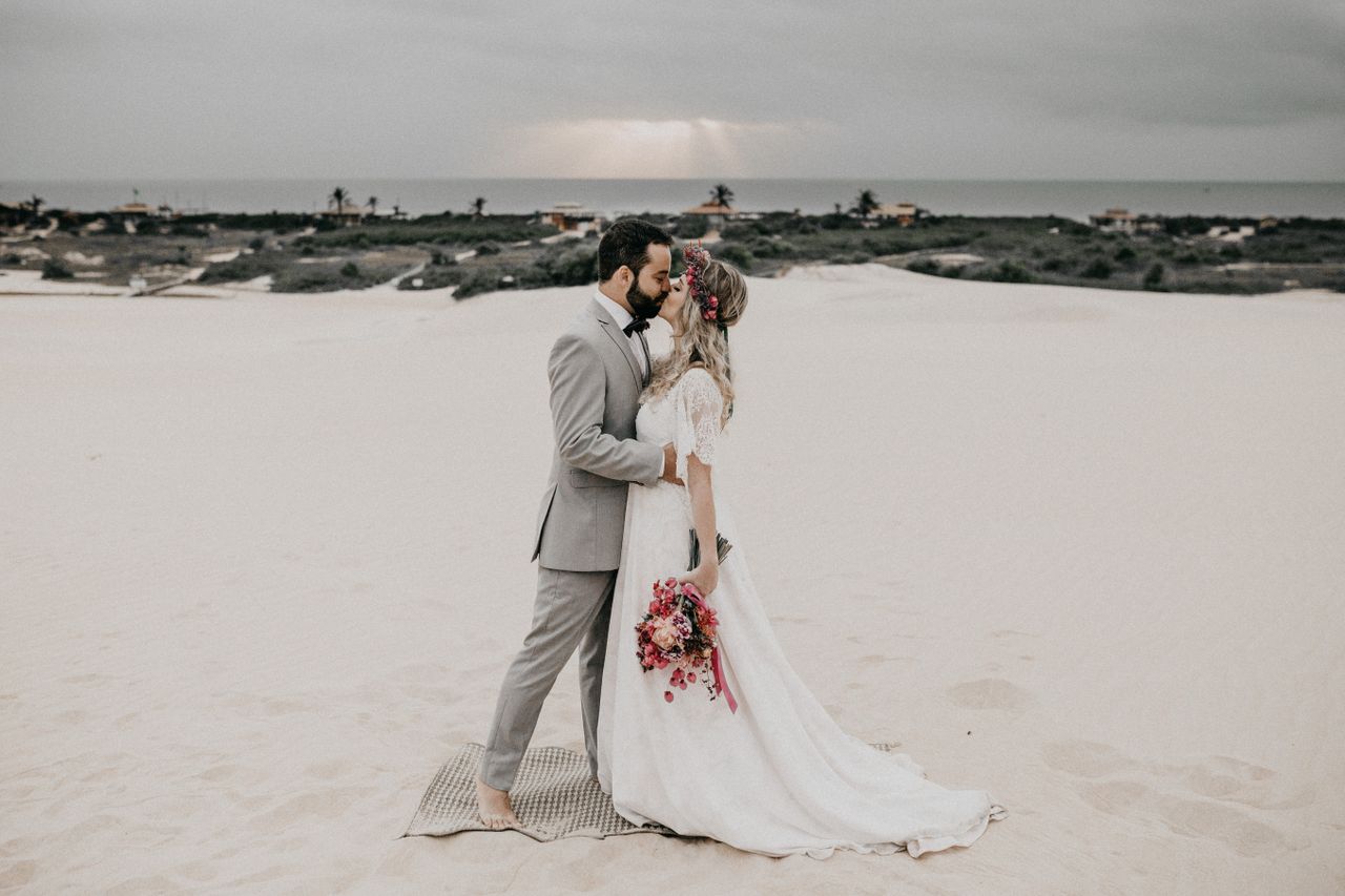 Elegant bride and groom sharing a romantic kiss on a serene beach at dusk.