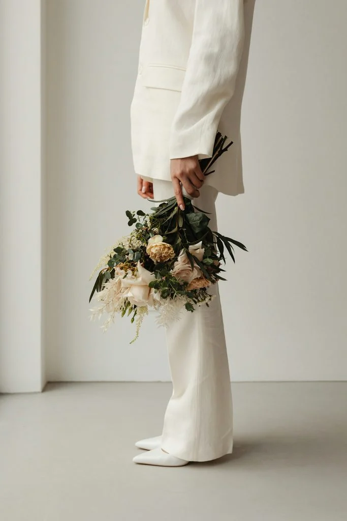 Bride in a white suit holding a bouquet