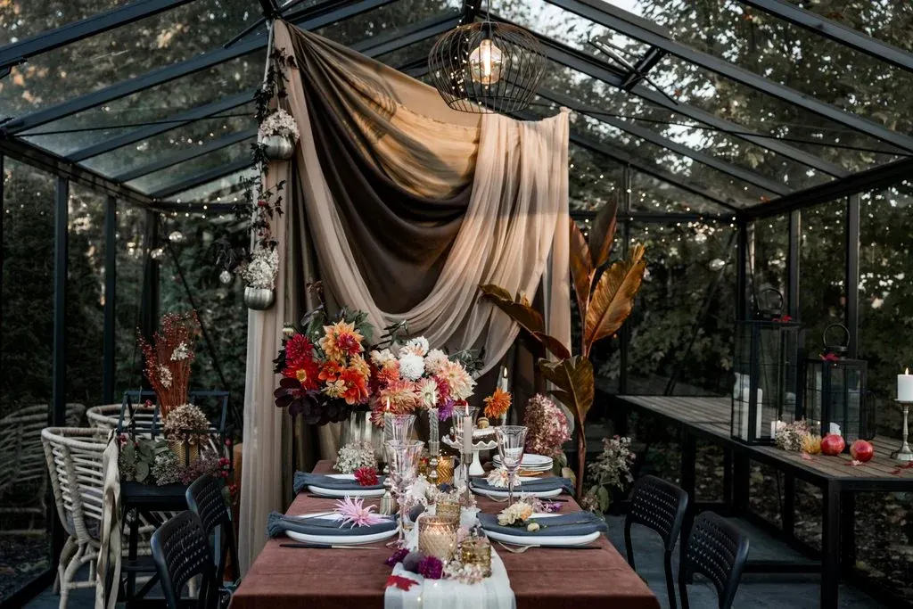 Wedding reception table with colourful flowers beneath draped fabric