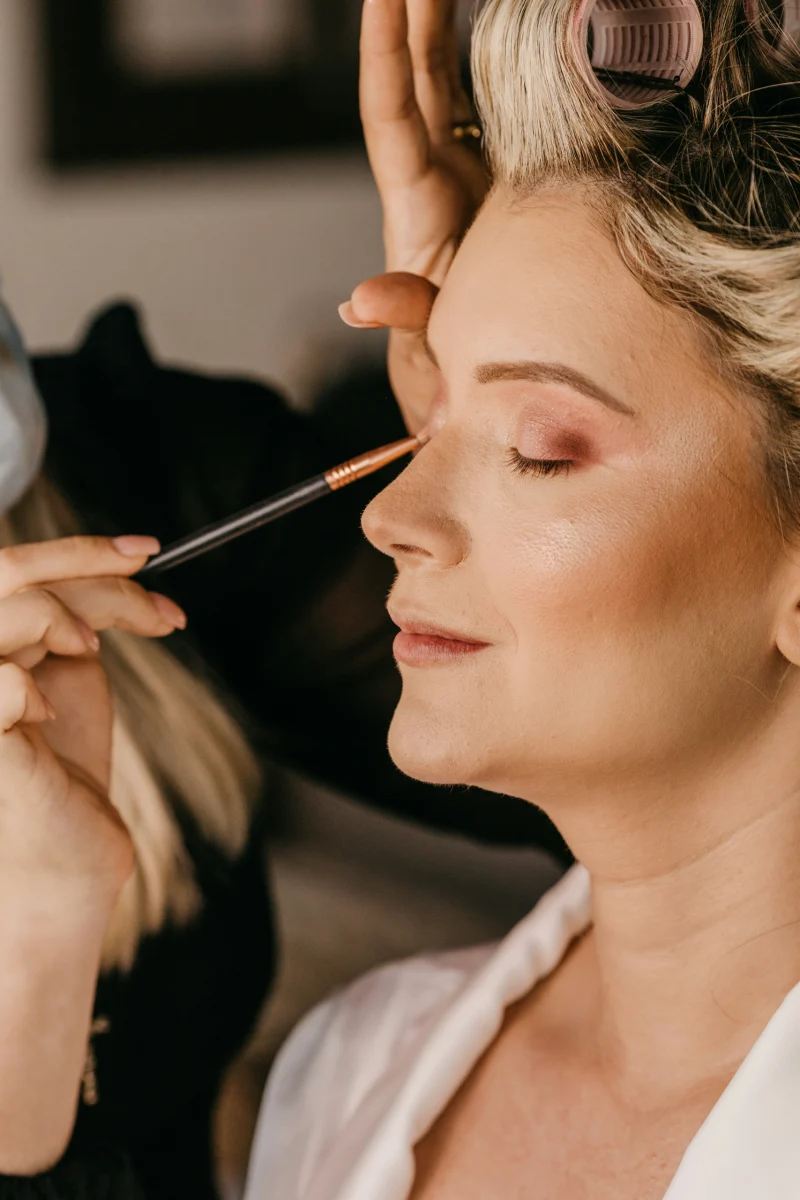 Bride having her eye makeup applied during wedding preparations.